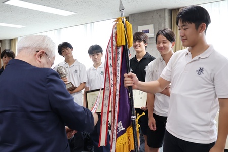 優勝旗につけられた成城学園のペナントを手にする学園長